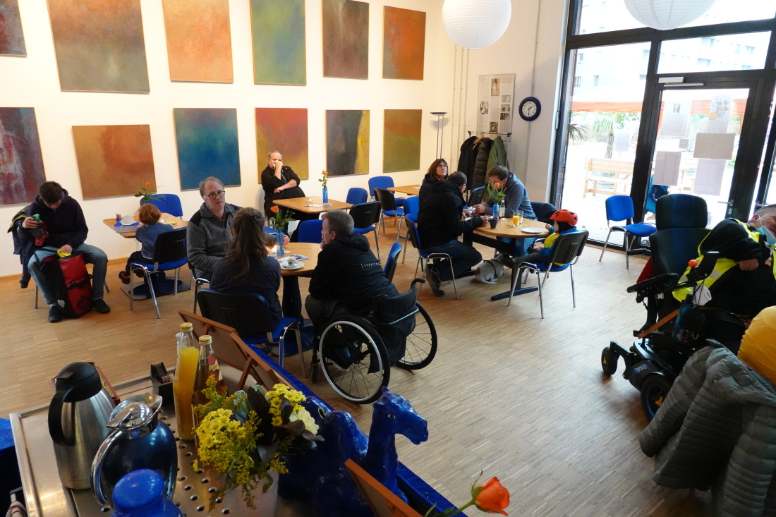 Menschen kommen an Tischen im Café der Blauen Manege für den Austausch zusammen.